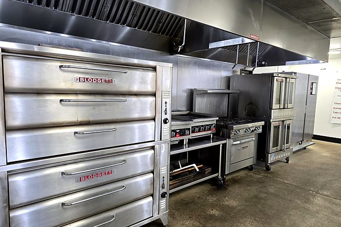 Stacked commercial deck ovens beside a stainless prep line in the Frontier Kitchen Pittsburgh bakery area.